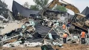 a demolished building site in Abuja with rubble and enforcement vehicles